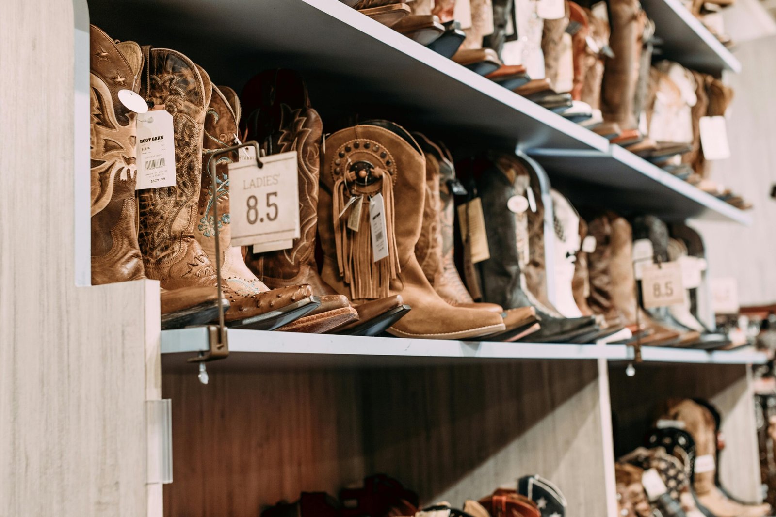 Variety of cowboy boots displayed on shelves in a fashionable footwear store.